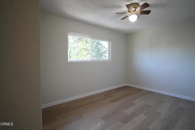 an empty room with a window and a fan