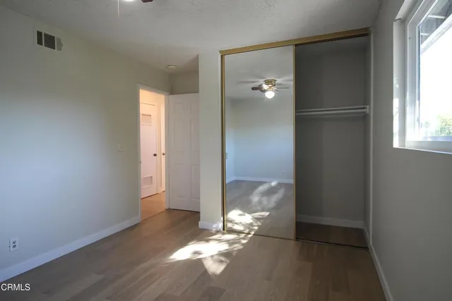 a view of empty room with wooden floor and fan