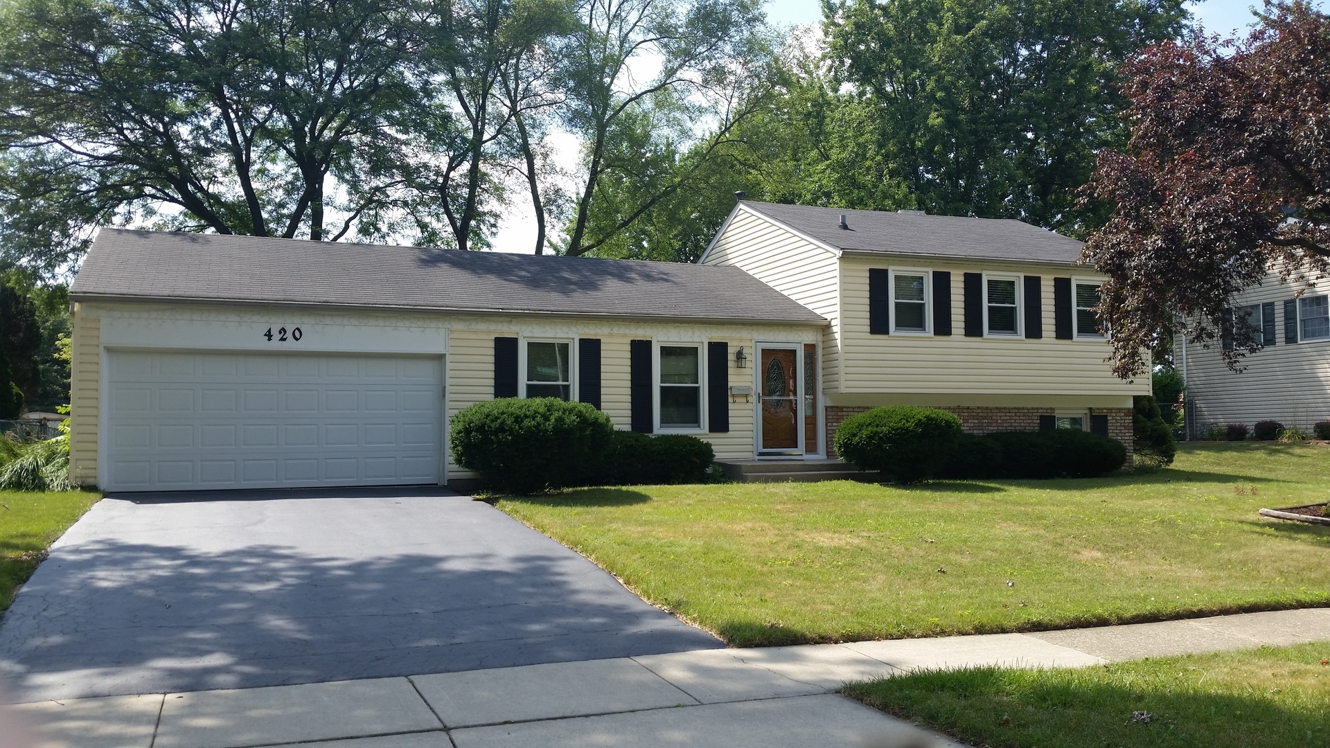 a front view of a house with yard and green space