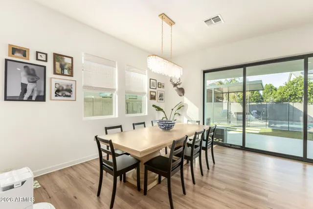 a kitchen with stainless steel appliances kitchen island granite countertop a sink a stove a dining table and chairs with wooden floor