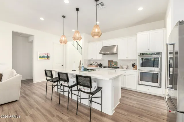 a kitchen with stainless steel appliances a stove a sink a refrigerator and a wooden floor