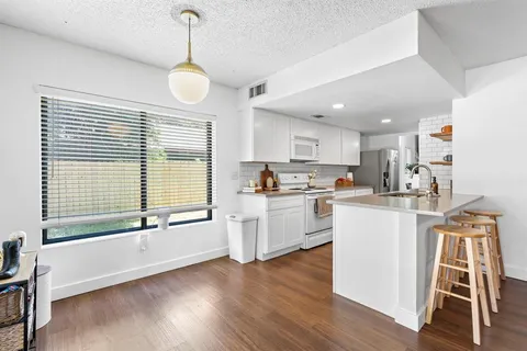 a open kitchen with white cabinets and wooden floor