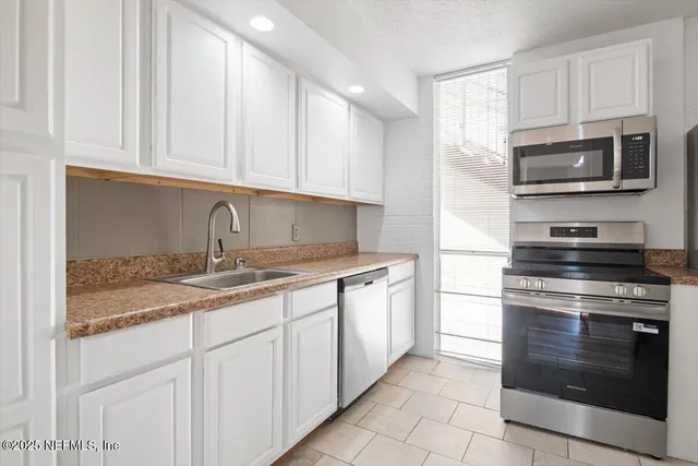a kitchen with stainless steel appliances granite countertop white cabinets a sink a stove and dishwasher