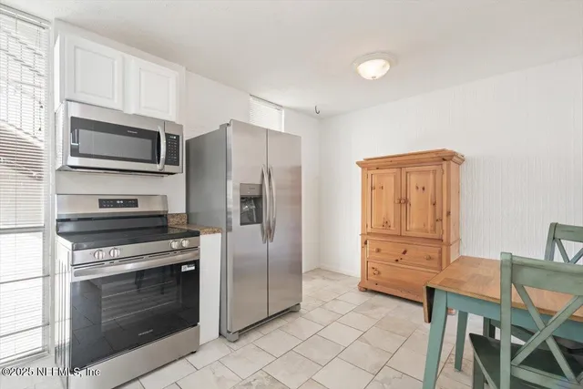 a kitchen with granite countertop a stove microwave and refrigerator