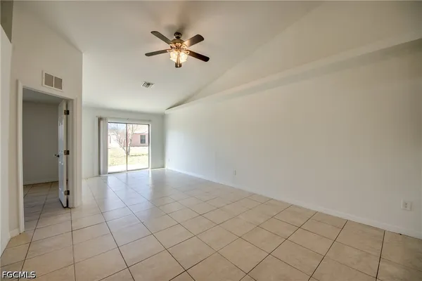 a view of an empty room and chandelier fan