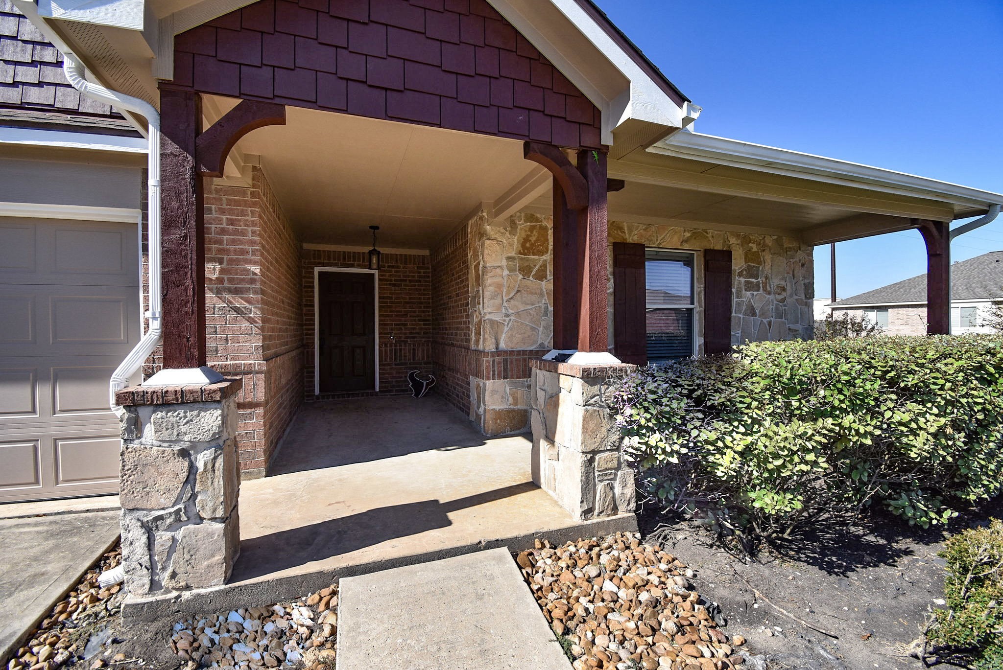 8502 Parapet Place Rosharon, TX 77583 - Photo 3 of 34 Warm rustic vibes --- with stone elevation/wood columns entry columns --- invites us into the recessed covered entry and a generous, open front porch, right. Inside, the single story home are 4 bedrooms and 2 full baths, gracing a 6,150 square-foot-lot with 2,314 square-feet of interior space.
