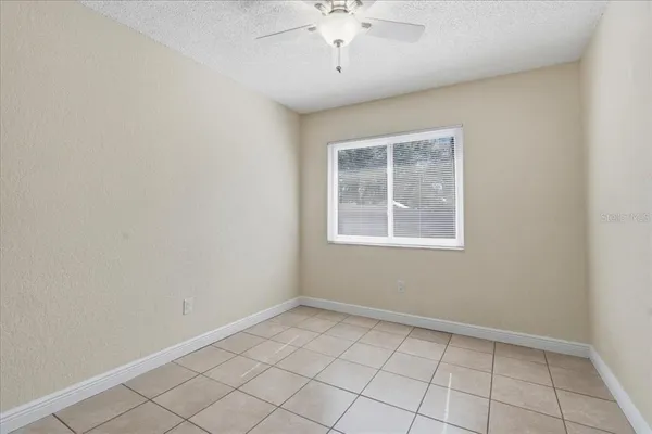 an empty room with windows and fan