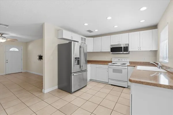 a kitchen with a refrigerator a sink and white cabinets