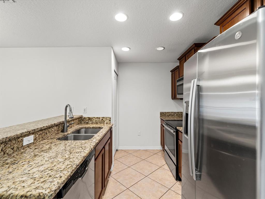 9779 Trumpet Vine Loop Trinity, FL 34655 - Photo 11 of 33 a kitchen with stainless steel appliances granite countertop a sink and a refrigerator