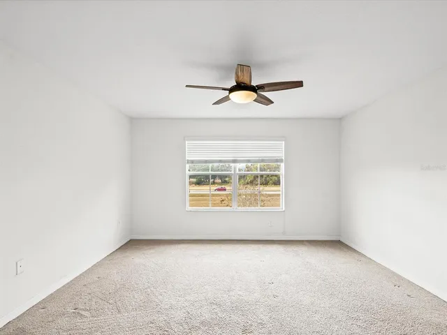 an empty room with a ceiling fan and window