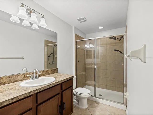 a bathroom with a granite countertop sink a toilet a mirror and shower