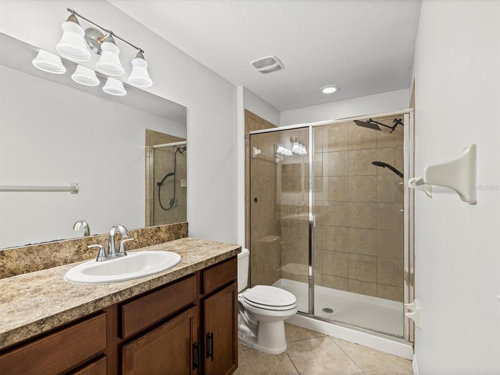 9779 Trumpet Vine Loop Trinity, FL 34655 - Photo 15 of 33 a bathroom with a granite countertop sink a toilet a mirror and shower
