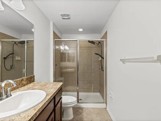 a bathroom with a granite countertop sink a toilet and shower