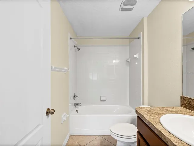 a bathroom with a granite countertop bathtub shower sink vanity mirror and toilet