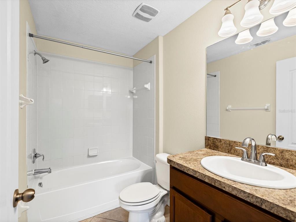9779 Trumpet Vine Loop Trinity, FL 34655 - Photo 21 of 33 a bathroom with a granite countertop sink mirror toilet and bathtub
