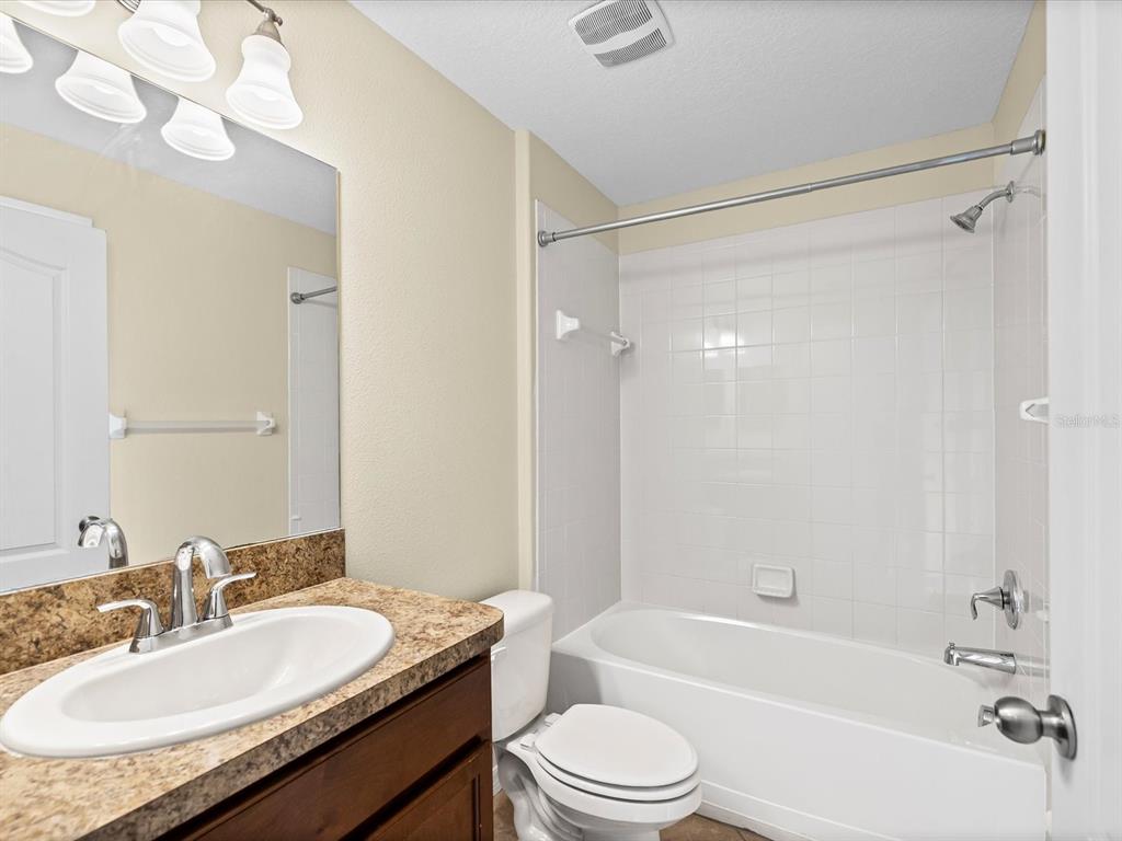 9779 Trumpet Vine Loop Trinity, FL 34655 - Photo 25 of 33 a bathroom with a granite countertop sink mirror toilet and bathtub