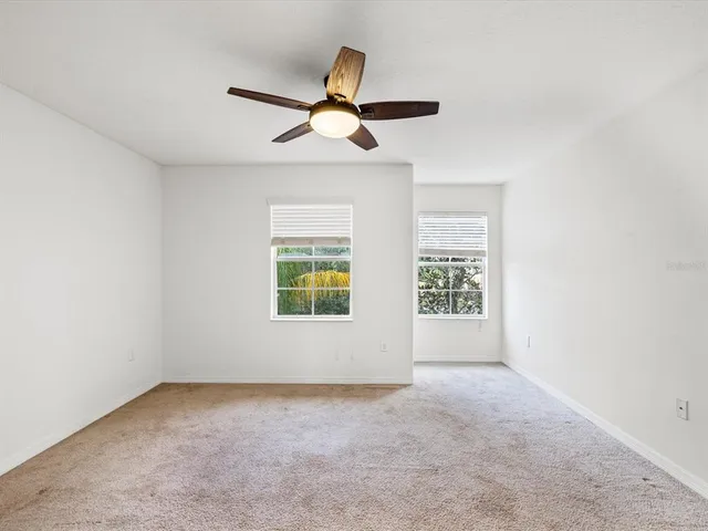 an empty room with windows and fan