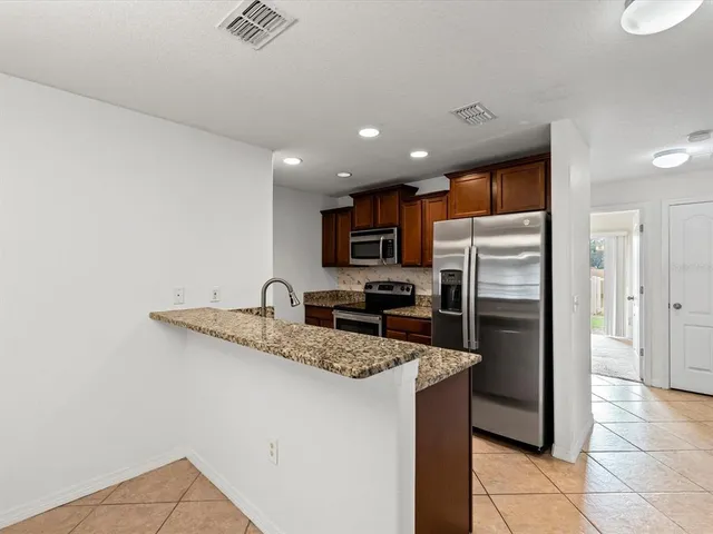 a kitchen with stainless steel appliances granite countertop a refrigerator a sink a stove a microwave and island