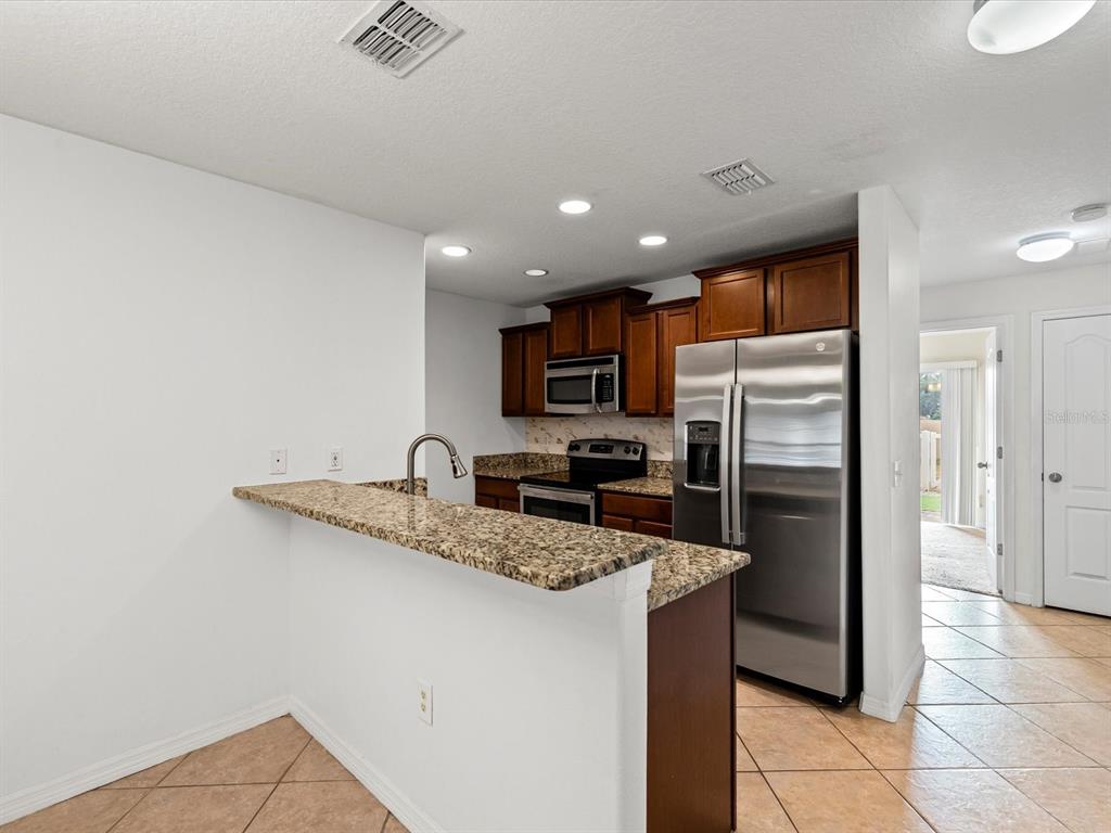 9779 Trumpet Vine Loop Trinity, FL 34655 - Photo 10 of 33 a kitchen with stainless steel appliances granite countertop a refrigerator a sink a stove a microwave and island