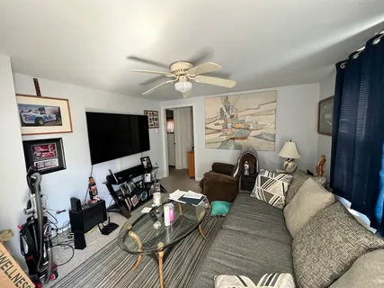 a living room with furniture ceiling fan and a flat screen tv