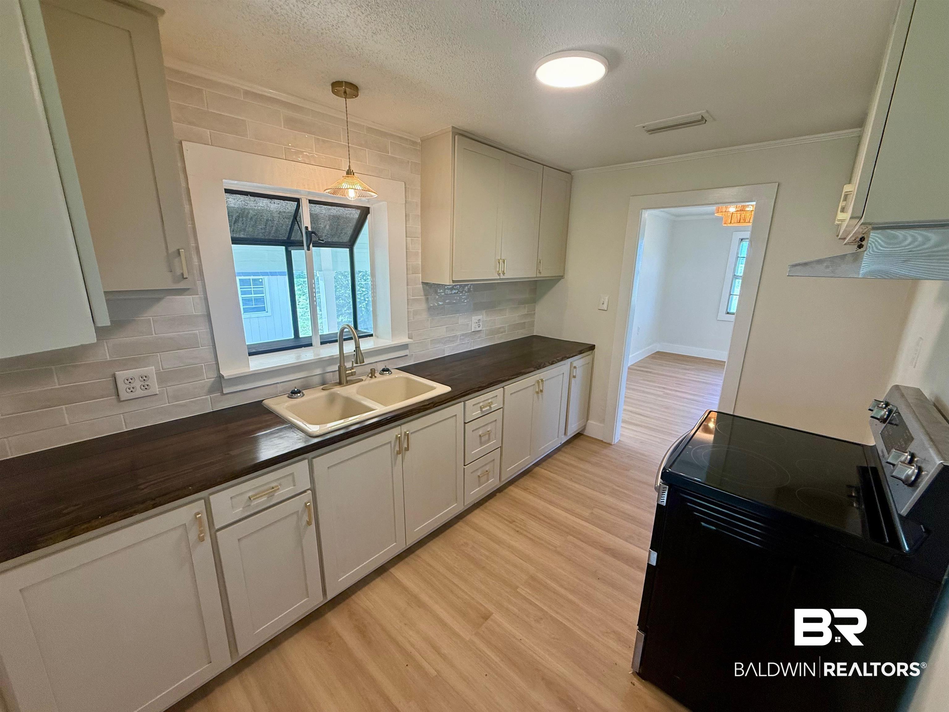 11698 Poser Road Foley, AL 36535 - Photo 9 of 20 Kitchen with black range with electric cooktop, light wood-style floors, decorative backsplash, decorative light fixtures, and a textured ceiling