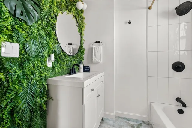 a bathroom with a sink and mirror with bathtub