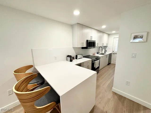 a living room with stainless steel appliances furniture a refrigerator and a view of kitchen