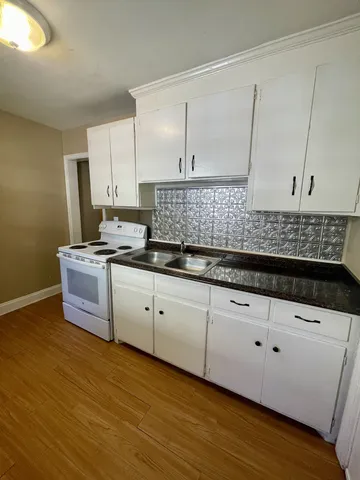 a kitchen with granite countertop a sink a stove and cabinets