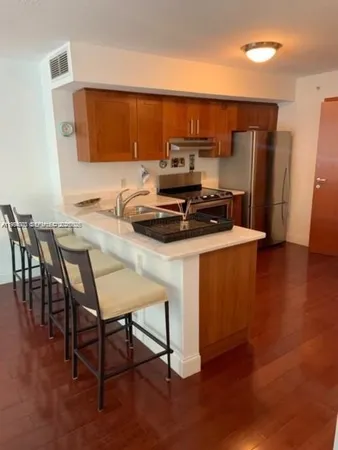 a kitchen with stainless steel appliances a stove a sink a microwave a dining table and chairs