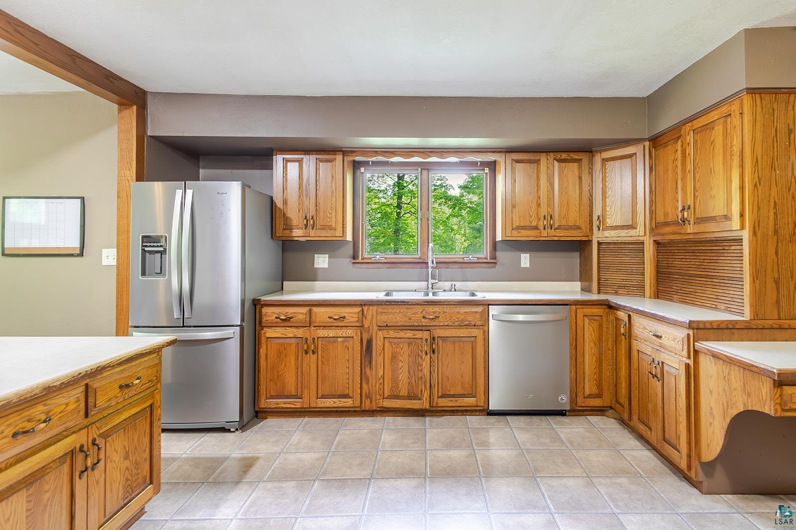 7045 Morris Thomas Road Cloquet, MN 55720 - Photo 7 of 28 Kitchen featuring extensive wood cabinetry, stainless steel appliances, and a central window above the sink