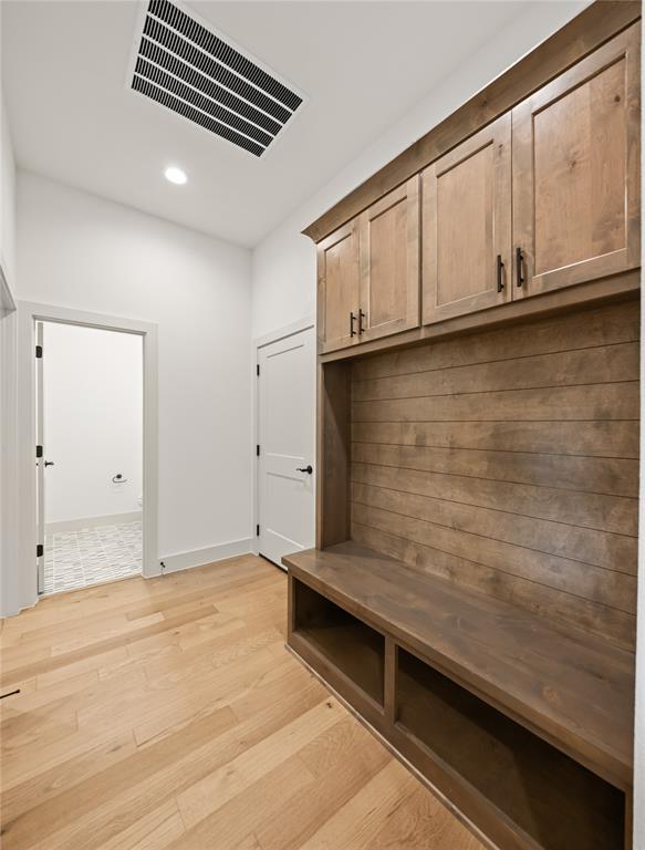 115 Red Bud Road Boyd, TX 76023 - Photo 19 of 38 Mudroom featuring built-in wood cabinetry with matte black hardware, integrated bench seating with open storage, and horizontal wood paneling