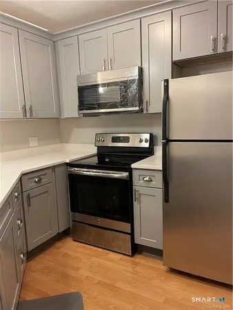 a kitchen with stainless steel appliances white cabinets white stove a refrigerator and a microwave