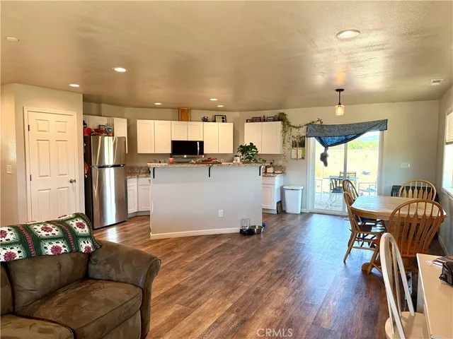 a living room with stainless steel appliances furniture and a wooden floor