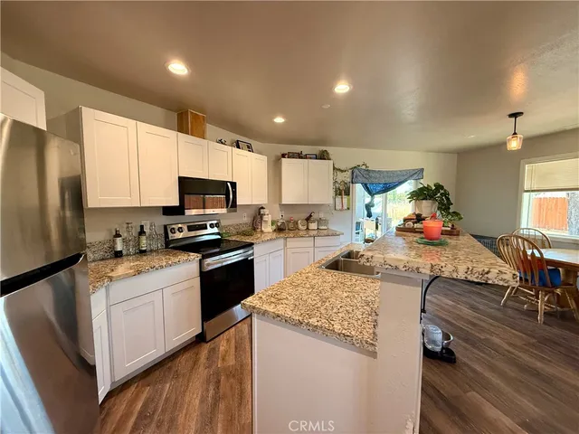 a large kitchen with granite countertop a sink stainless steel appliances and cabinets