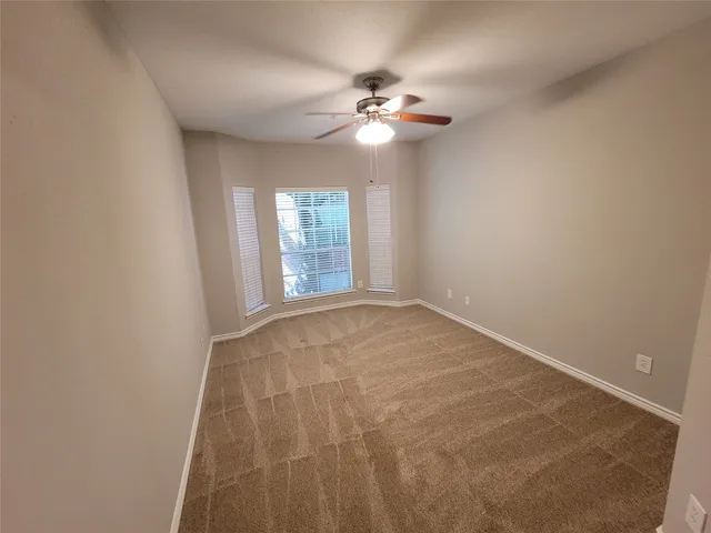 a view of an empty room with a chandelier fan