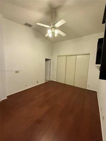 an empty room with wooden floor and fan