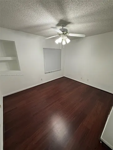 an empty room with wooden floor fan and window