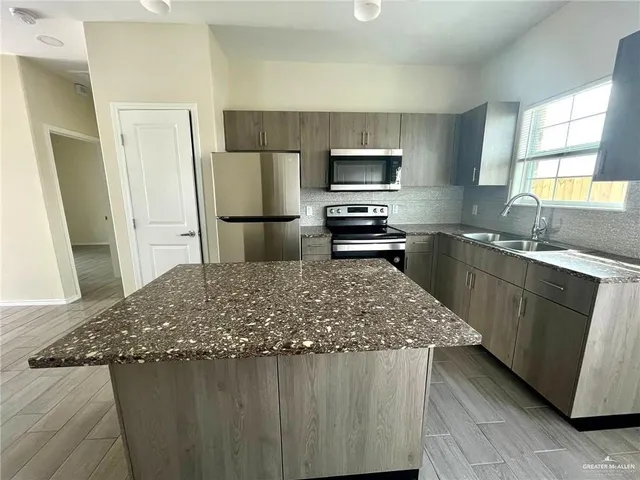 a kitchen with stainless steel appliances granite countertop a sink stove and refrigerator