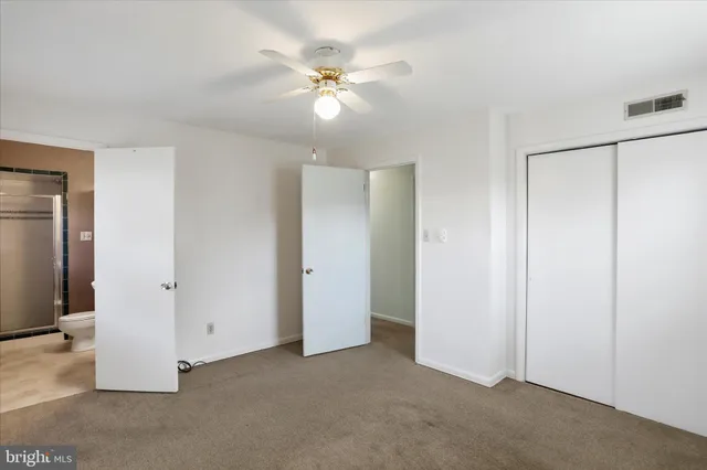 an empty room with closet and a chandelier fan