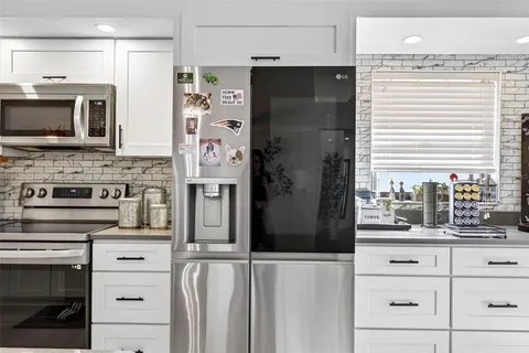 a kitchen with stainless steel appliances white cabinets and a refrigerator
