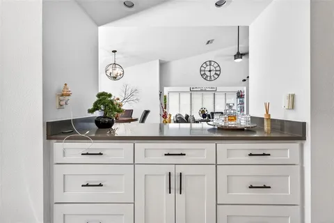 a kitchen with white cabinets and a clock on the wall