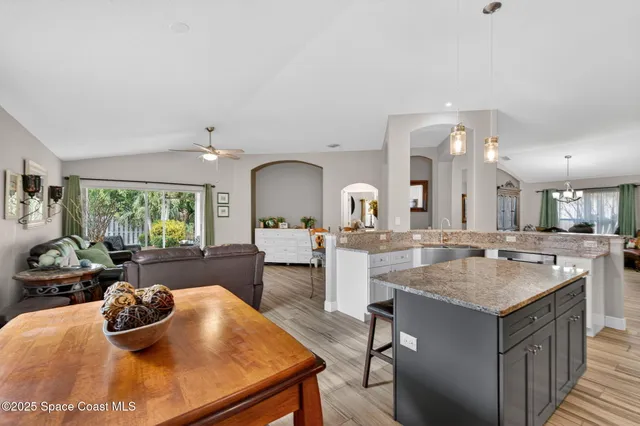 a kitchen with a sink a counter top space and living room view