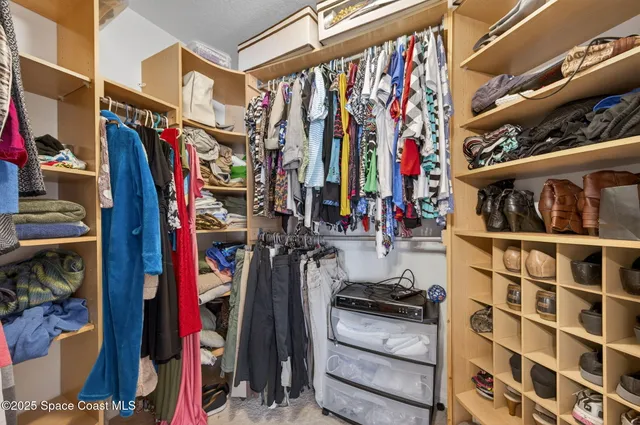 a view of walk in closet with clothes and shoes