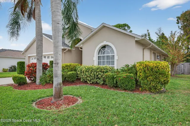 a front view of a house with a yard and potted plants