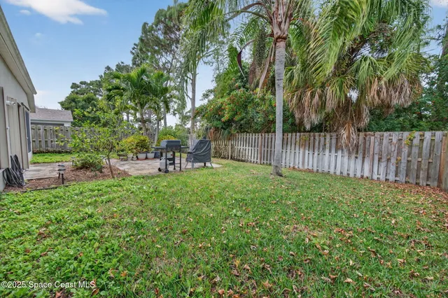 a view of a backyard with table and chairs and a large tree