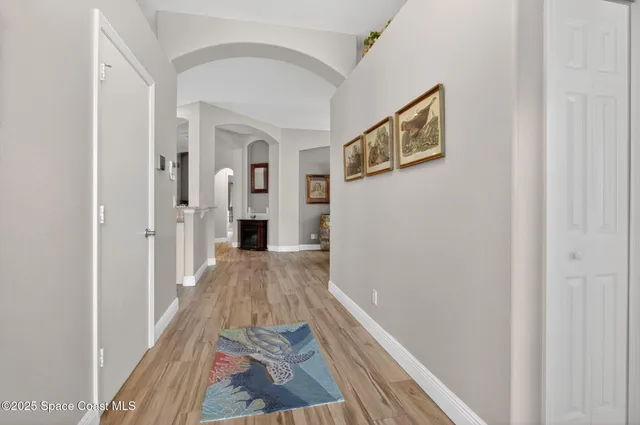 a view of a hallway with wooden floor and a bathroom