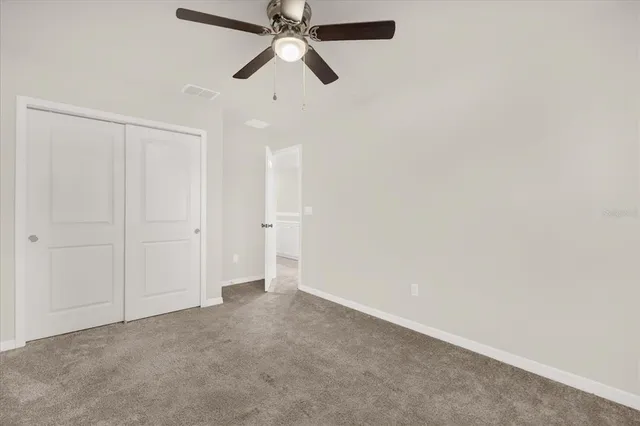 an empty room with closet and a chandelier fan