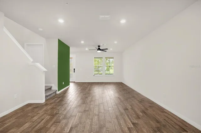 an empty room with wooden floor chandelier and windows