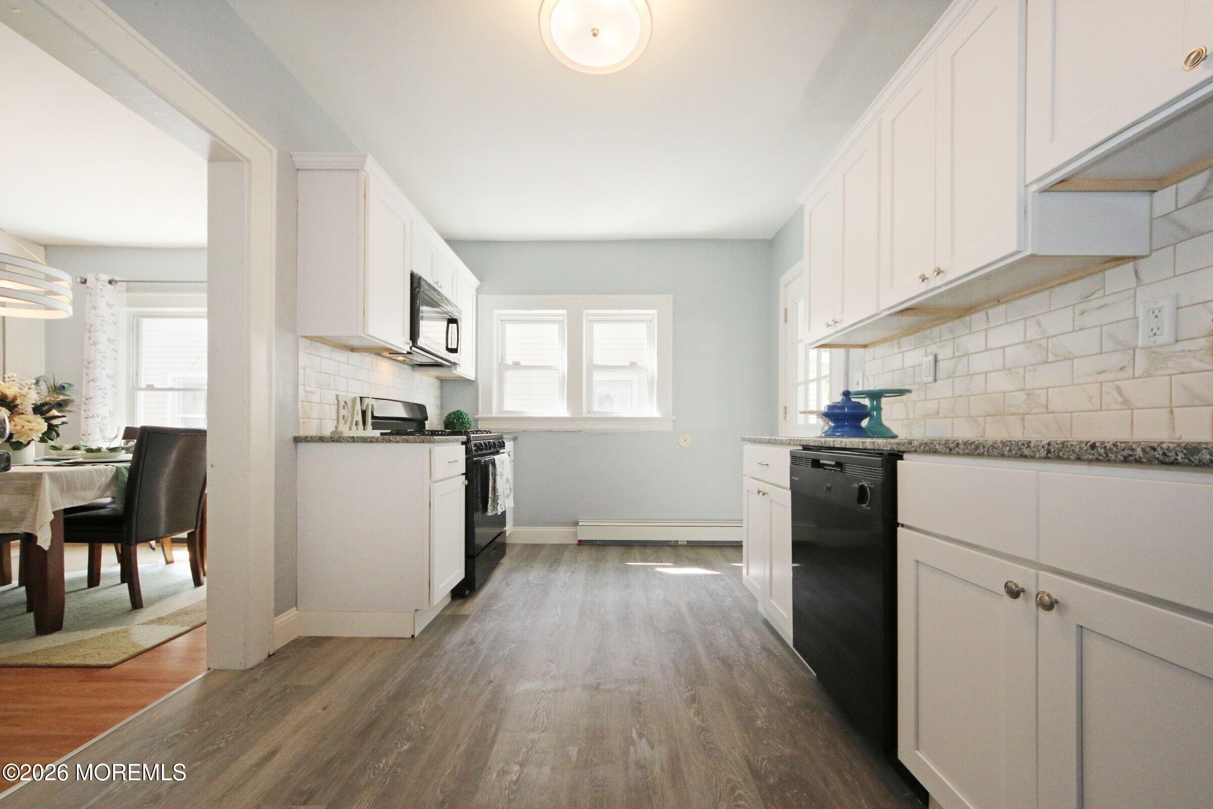 183 Ridge Avenue Asbury Park, NJ 07712 - Photo 12 of 23 a kitchen with granite countertop a refrigerator oven a sink dishwasher and white cabinets with wooden floor