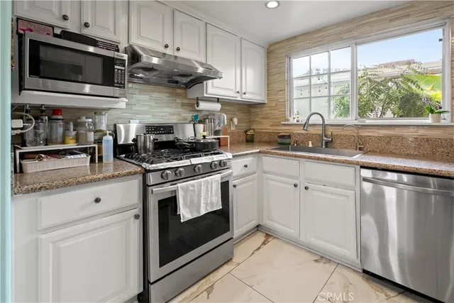 a kitchen with granite countertop cabinets stainless steel appliances and a window